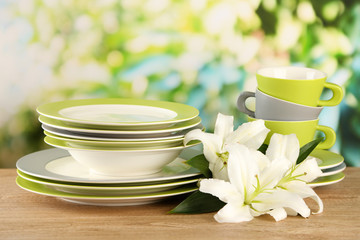 Empty plates and cups on wooden table on green background