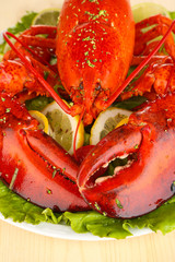 Red lobster on platter with vegetables on wooden table close-up