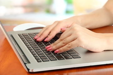 Fototapeta na wymiar Female hands writing on laptop, on bright background