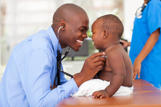 happy african male doctor examining baby boy