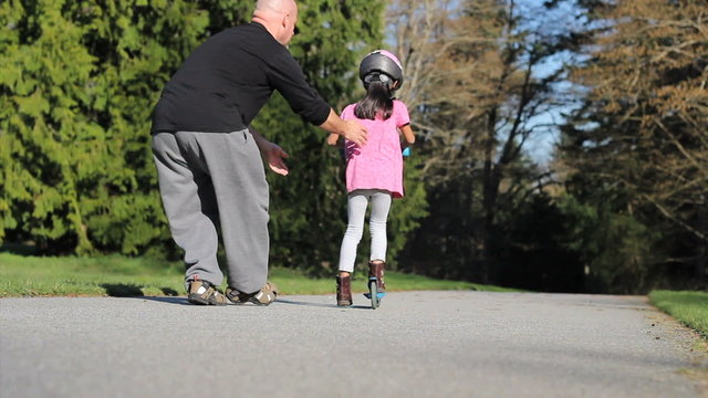 Proud Dad Helps Daughter Ride Scooter-With Helmut