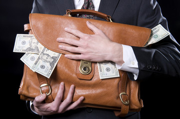 Closeup of man holding briefcase with money spilling out