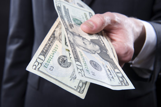Closeup of man in suit offering cash