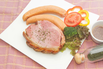 smoke ham steak with smoked sausage on the white plate