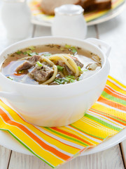 nutritious meat soup with pasta in a white tureen