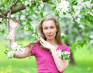 young attractive woman standing near the blossoming apple tree 