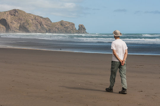 man walking on Waitakere beach