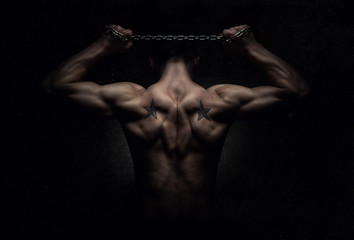 Muscular sports man stretching out over dark background