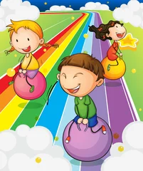Fototapeten Drei Kinder spielen mit den Hüpfbällen an der bunten Straße © GraphicsRF