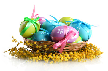 Easter eggs in basket and mimosa flowers, isolated on white