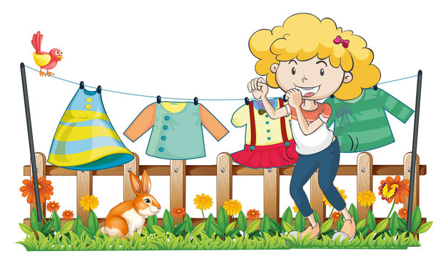 A lady hanging her clothes in the garden near the wooden fence