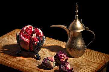 Vintage still life - pomegranate, dried roses and arabic teapot