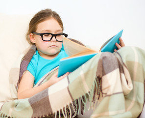 Little girl is reading a book
