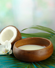 Coconut with leaves and flower, on blue wooden background