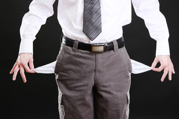 Business man showing his empty pockets, on black background