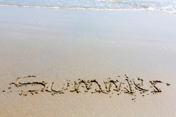 Summer handwritten inscription in sand on a beach