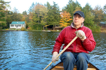 Man paddling a canoe in Vermont fall foliage