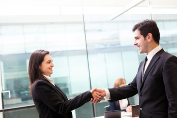 Business handshake at modern office with bussiness people on bac