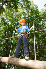 Young guy with equipment climber moves on balk holding ropes.