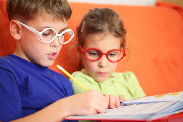 Girl and boy intently doing homework, focus on hinge glasses.