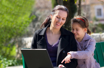 mother and daughter in the park with laptop