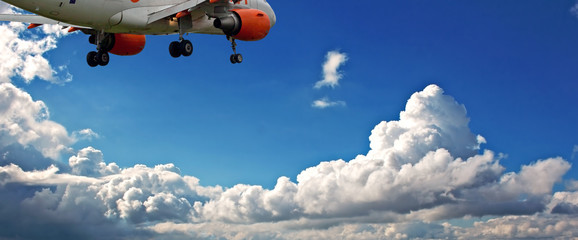 Obraz na płótnie Canvas Passenger jet against a blue sky with white fluffy clouds