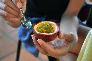Girl eating a passion fruit with a spoon