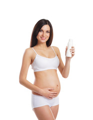A happy brunette pregnant woman in ligerie and holding a bottle