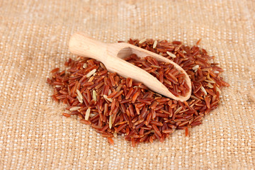 red rice on sacking  in wooden  scoop