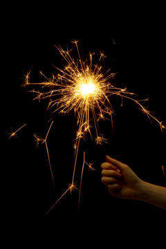 beautiful sparkler in woman hand on black background.