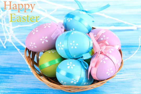 Easter eggs in basket, on blue wooden background