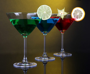 Alcoholic cocktails in martini glasses on dark yellow
