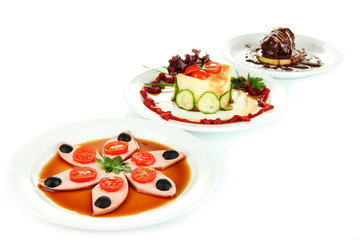Small portions of food on big white plates isolated on white