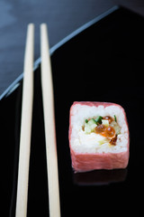 Sushi and chopsticks on a black plate, vertical shot