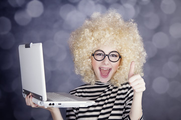 Portrait of funny girl in blonde wig with laptop. Studio shot.