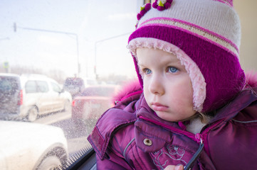 Adorable girl in winter clothes ride city bus and look to window © Joshhh