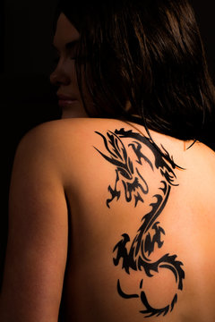 Beautiful female body with tribal dragon tattoo