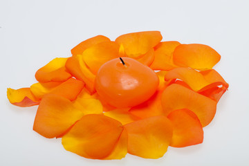 Fototapeta na wymiar Spilt petals of the orange-rose around the aromatic candle