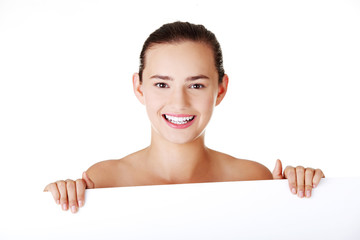 Beautiful teen girl behind big blank billboard