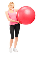 Full length portrait of a blond female athlete holding a pilates