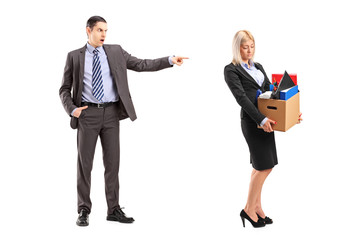 Full length portrait of an angry boss firing a woman with a box