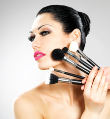 Beautiful woman with makeup brushes