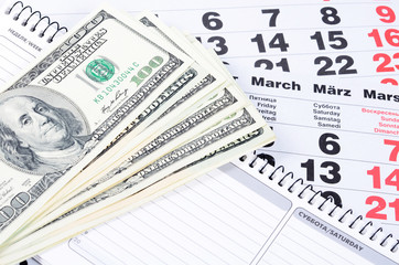 Fototapeta na wymiar Banknotes of dollars on calendar sheets closeup