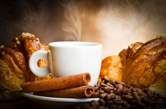 Coffee smoking on the coffee beans and croissant background