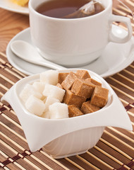 cubes of white and brown sugar and a cup of tea