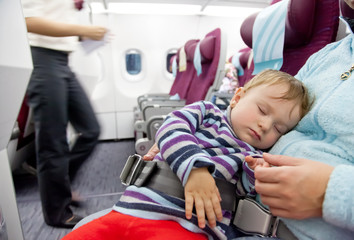 Mother and sleeping two year old baby girl travel on airplane
