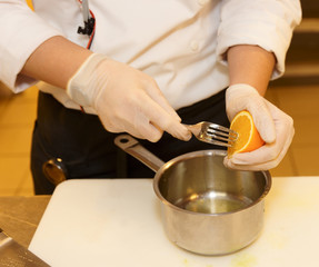 Chef is squeezing orange to make sauce
