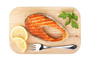 Grilled salmon with lemon slices and parsley on cutting board