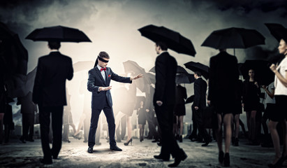 Businessman in blindfold among group of people