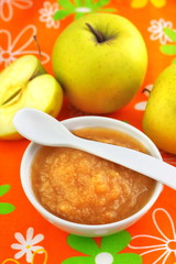 Homemade apple puree in a bowl on colorful tablecloth